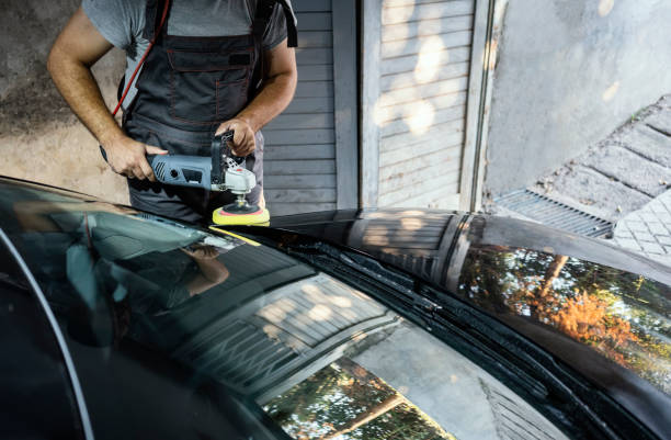Man polishing a car segment using an electric orbital polisher in garage
